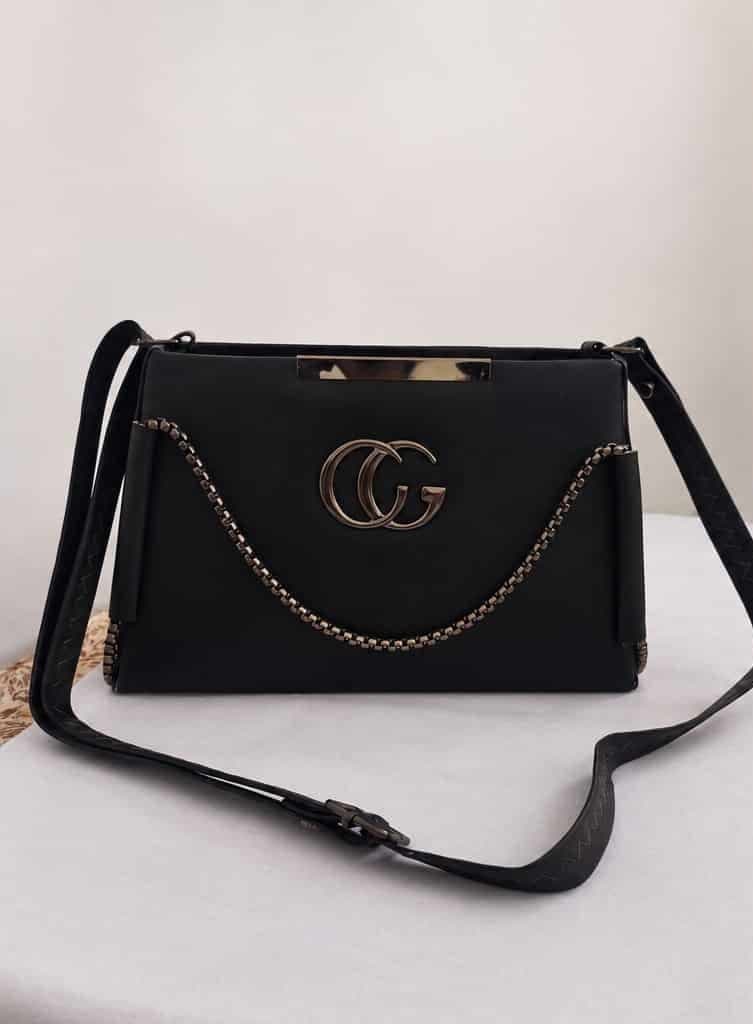 Black structured crossbody bag with chain detail — front view